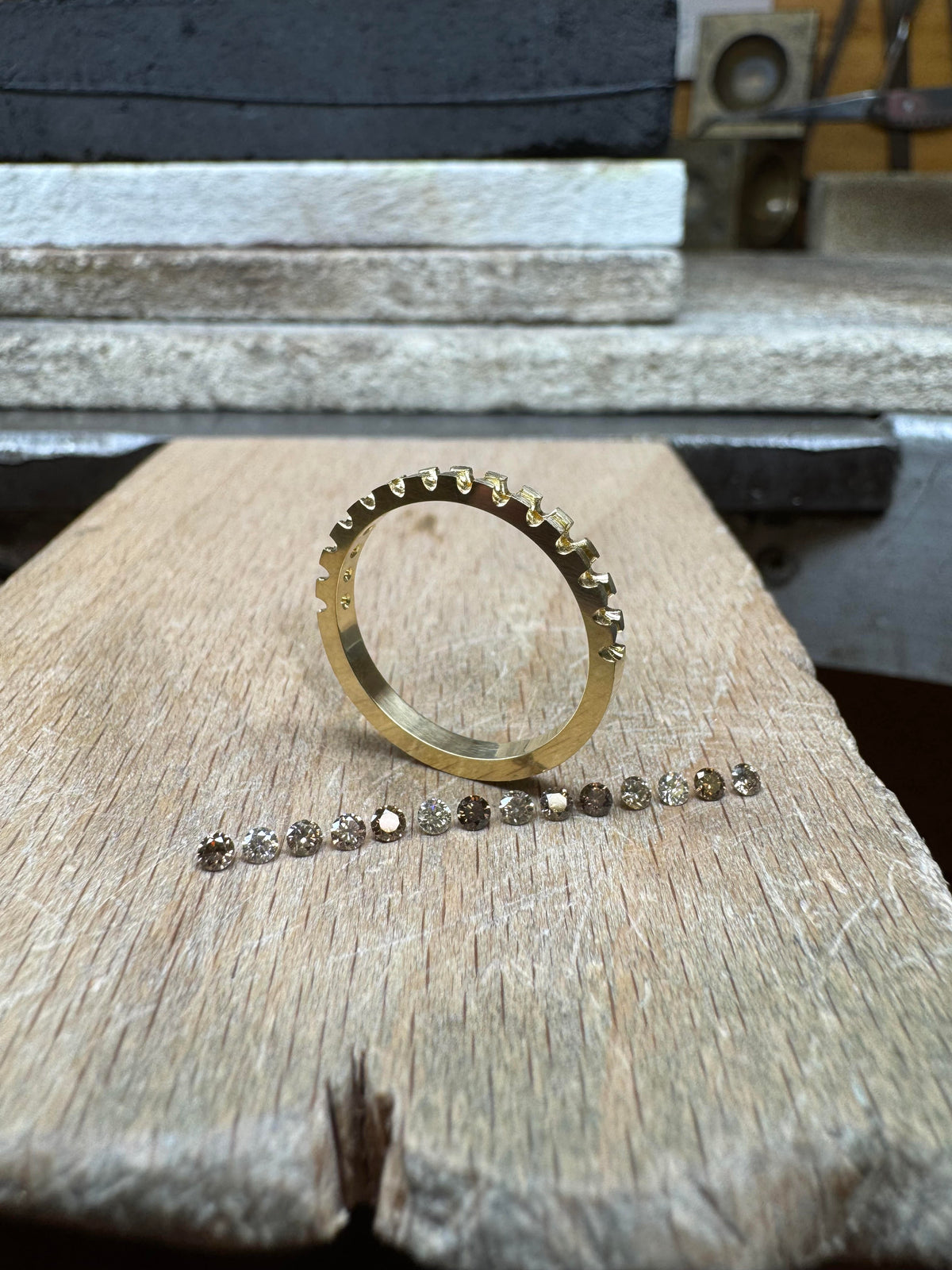 Montatura di anello in oro giallo 18 kt accanto a una scala cromatica di diamanti naturali brown e cognac, dal Top Light Brown alle classificazioni C1–C7
